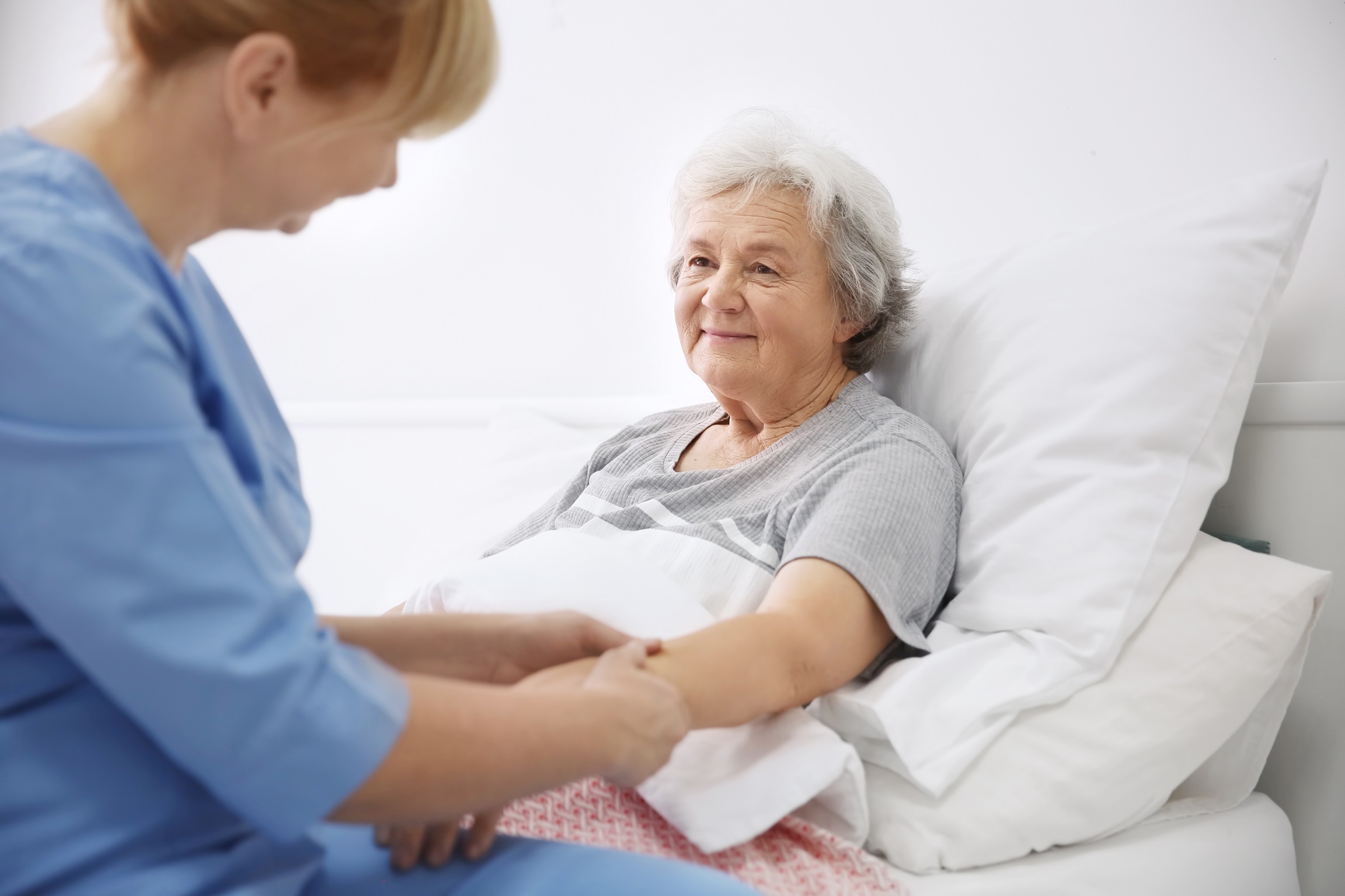 Krankenschwester massiert den Arm einer älteren Patientin