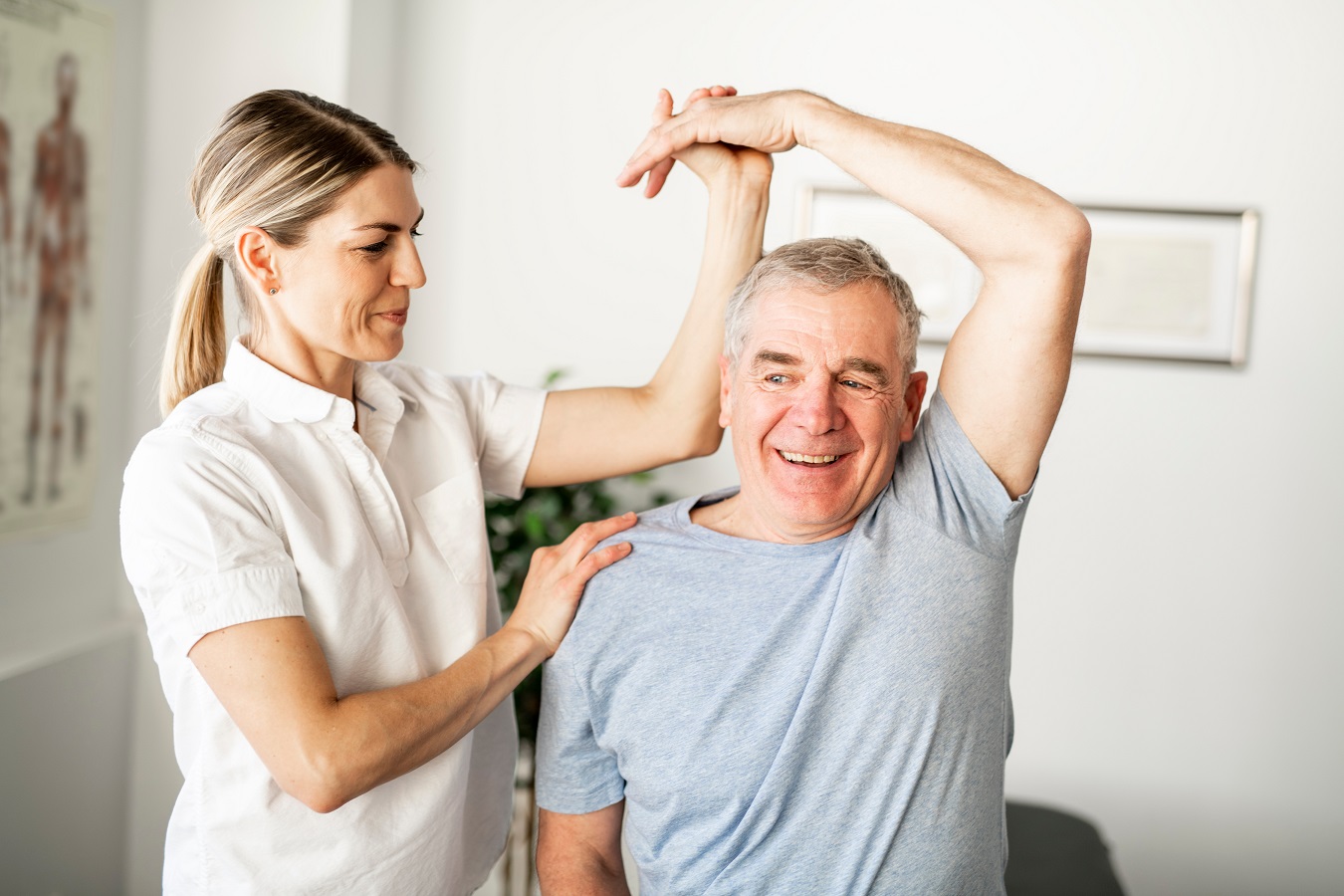 Die Therapeutin unterstützt den Patienten bei der Ausführung einer bestimmten Bewegung. Arm über Kopf.