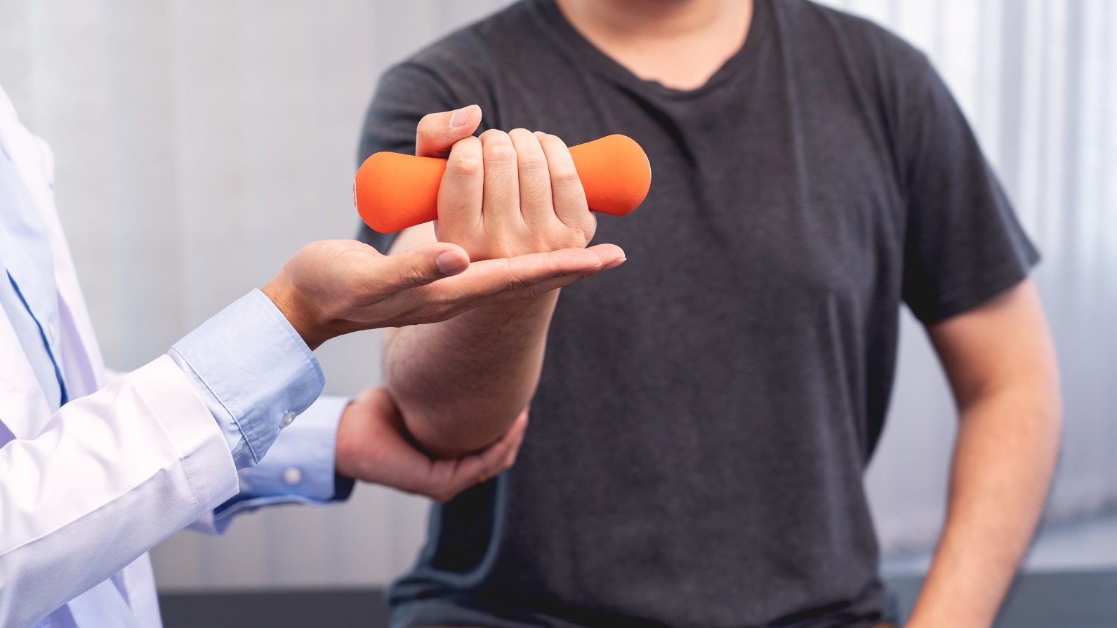 A doctor helping a patient to lift a dumbbell