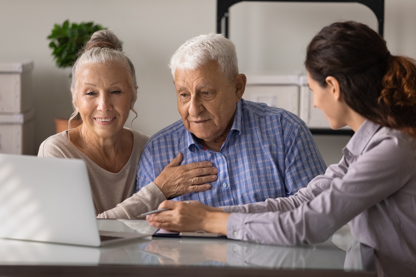 Eine Frau zeigt einem älteren Ehepaar Daten auf dem Computer