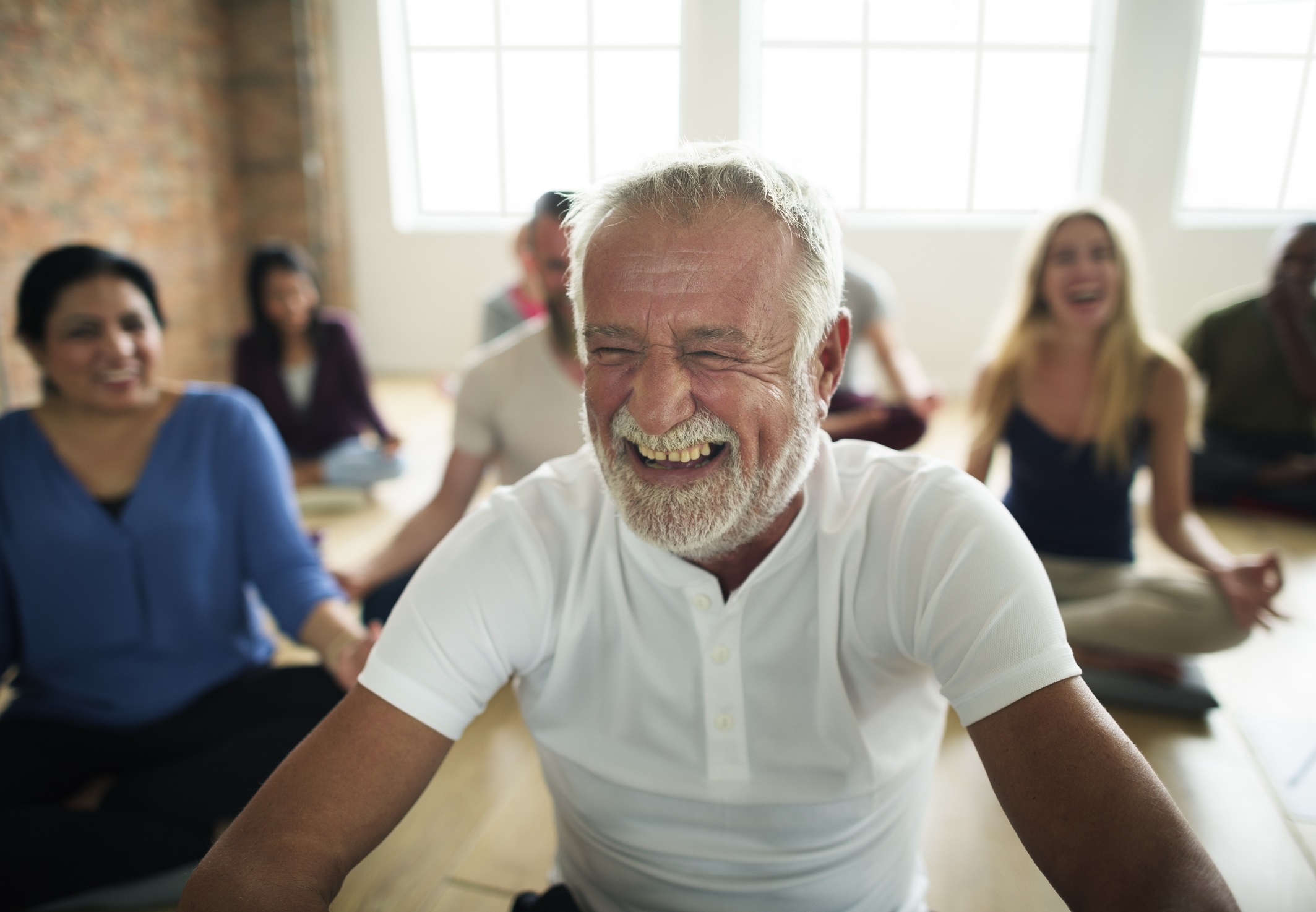 Mann lacht in einer Yoga Klasse