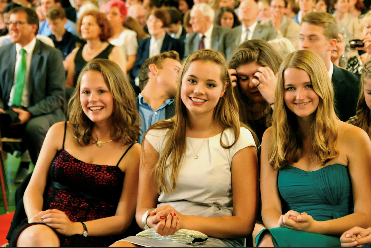 Drei junge Mädchen bei einer Feier sitzend im Publikum