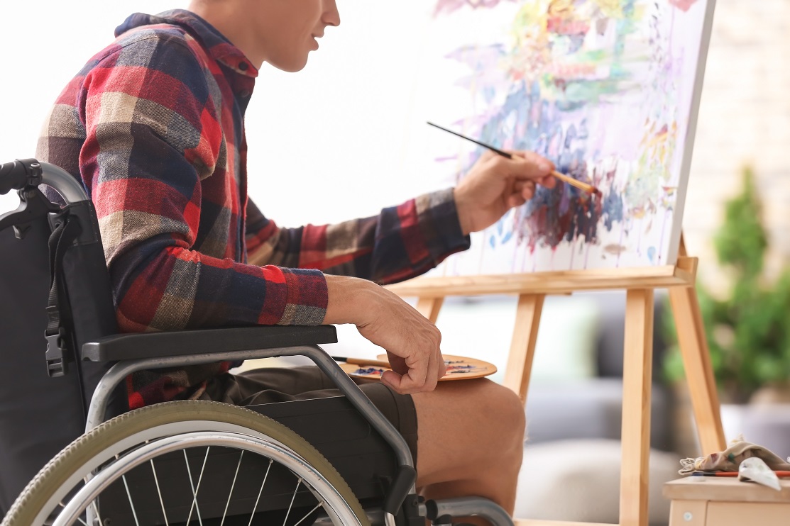 Young man in a wheelchair paints a picture