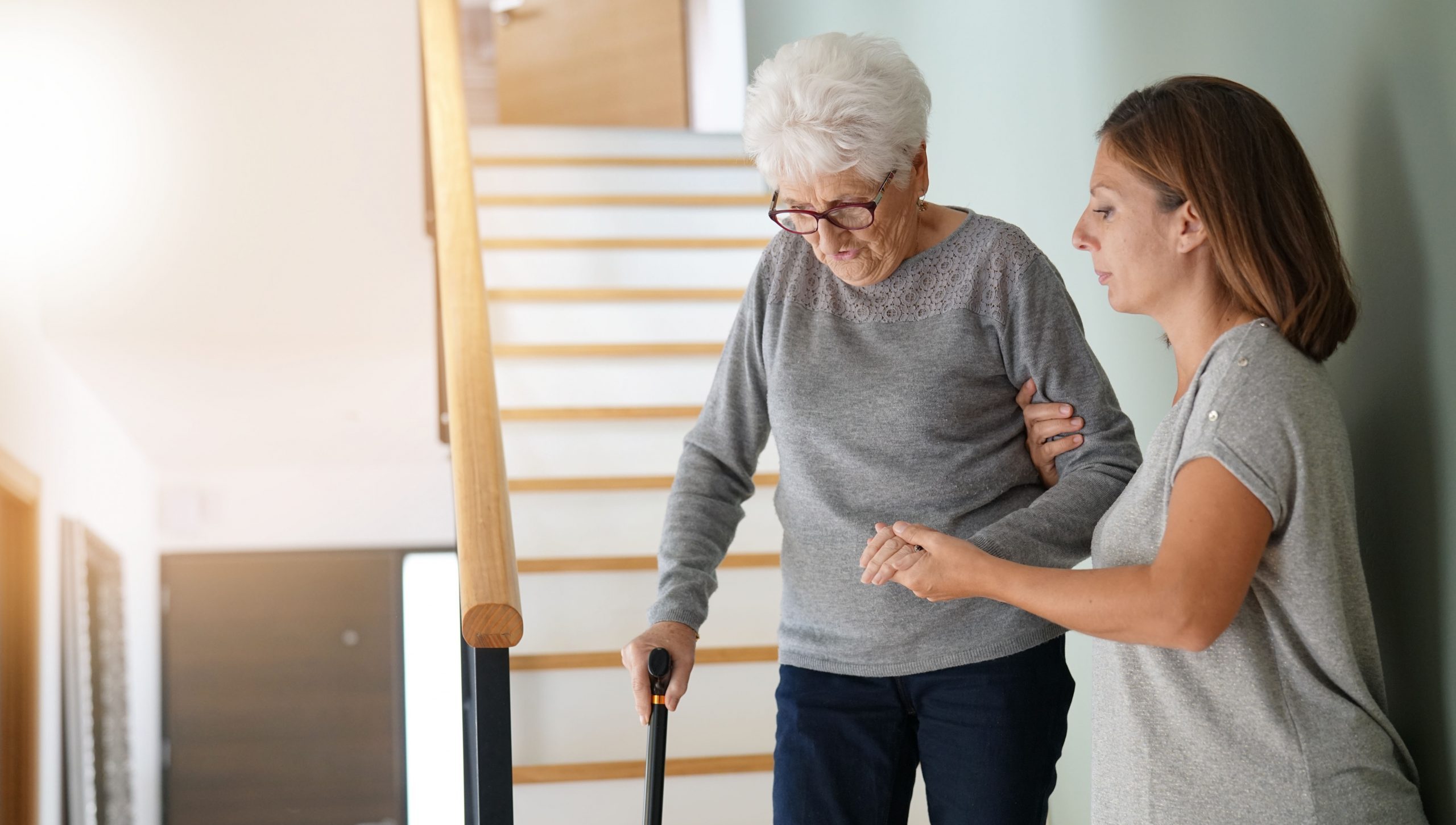 Junge Frau hilft älterer Frau auf der Treppe